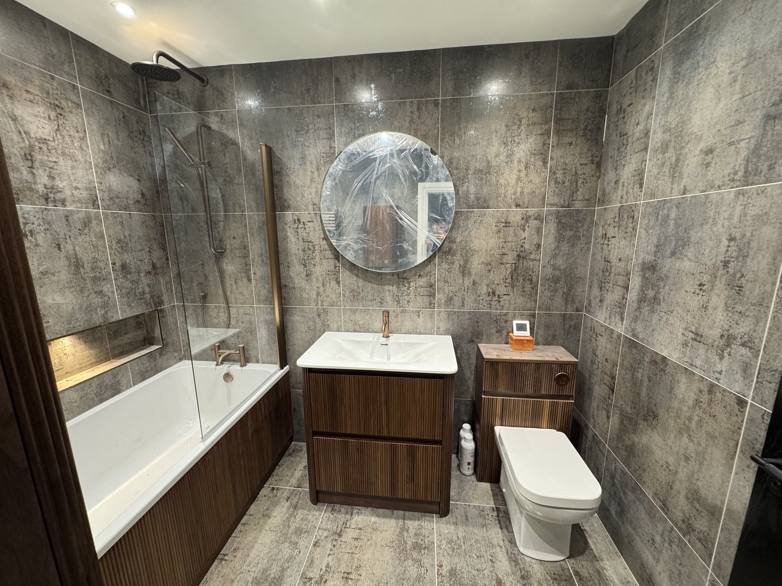 Wall-hung vanity unit and a round backlit mirror keep the room bright and uncluttered.