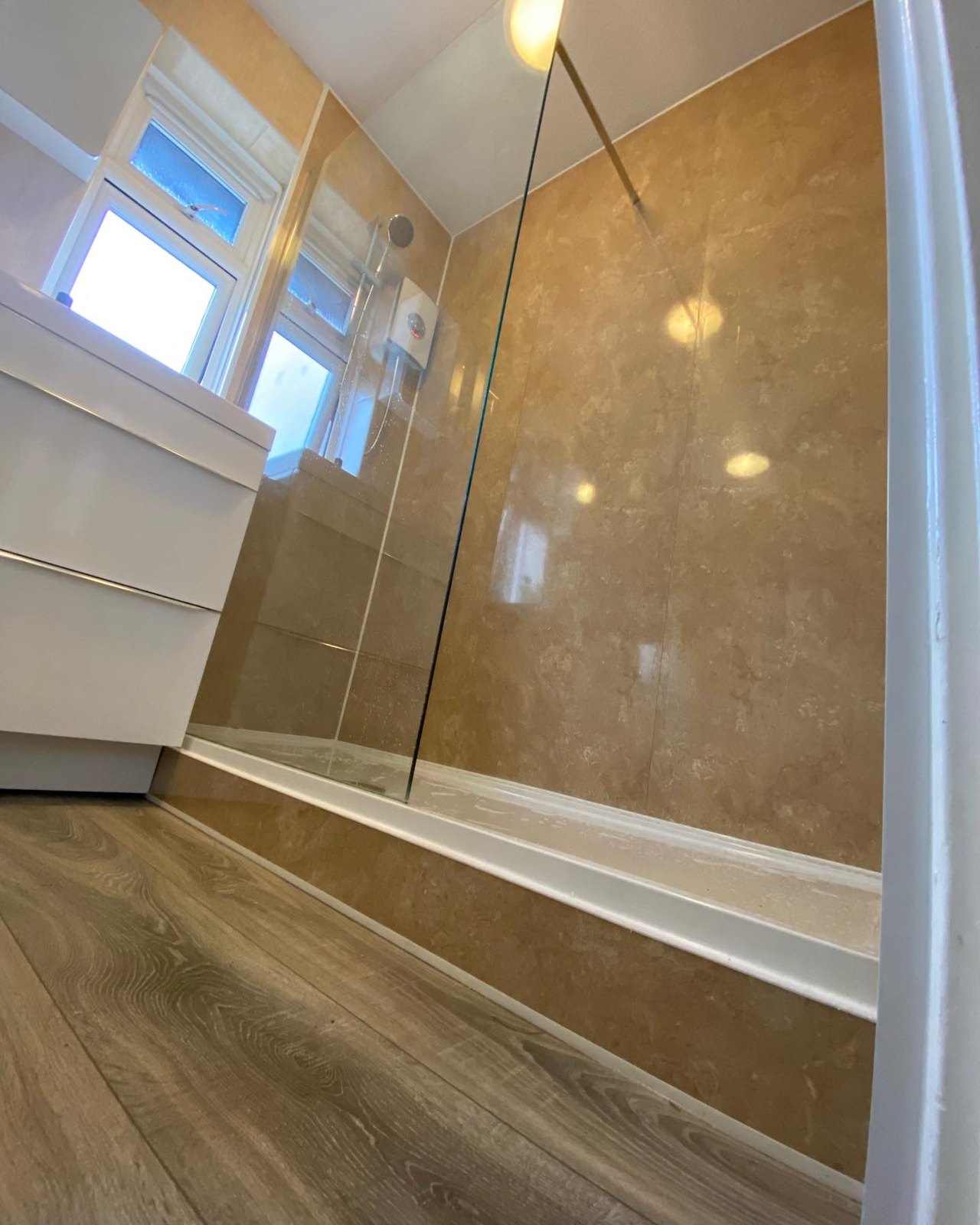 Electric shower, wood-effect flooring and a fitted vanity complete the room.